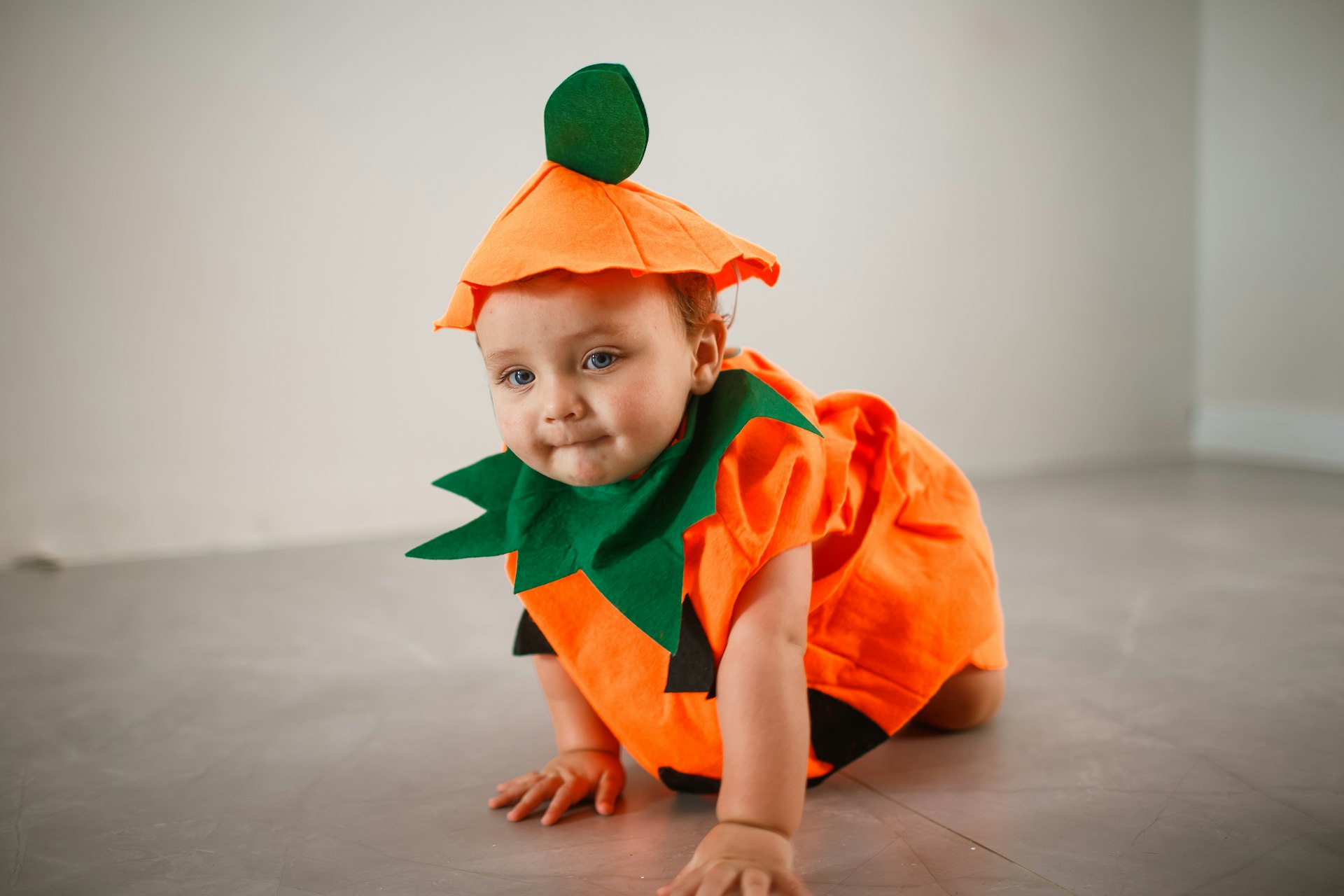 a baby dressed in a carrot costume crawling on the floor